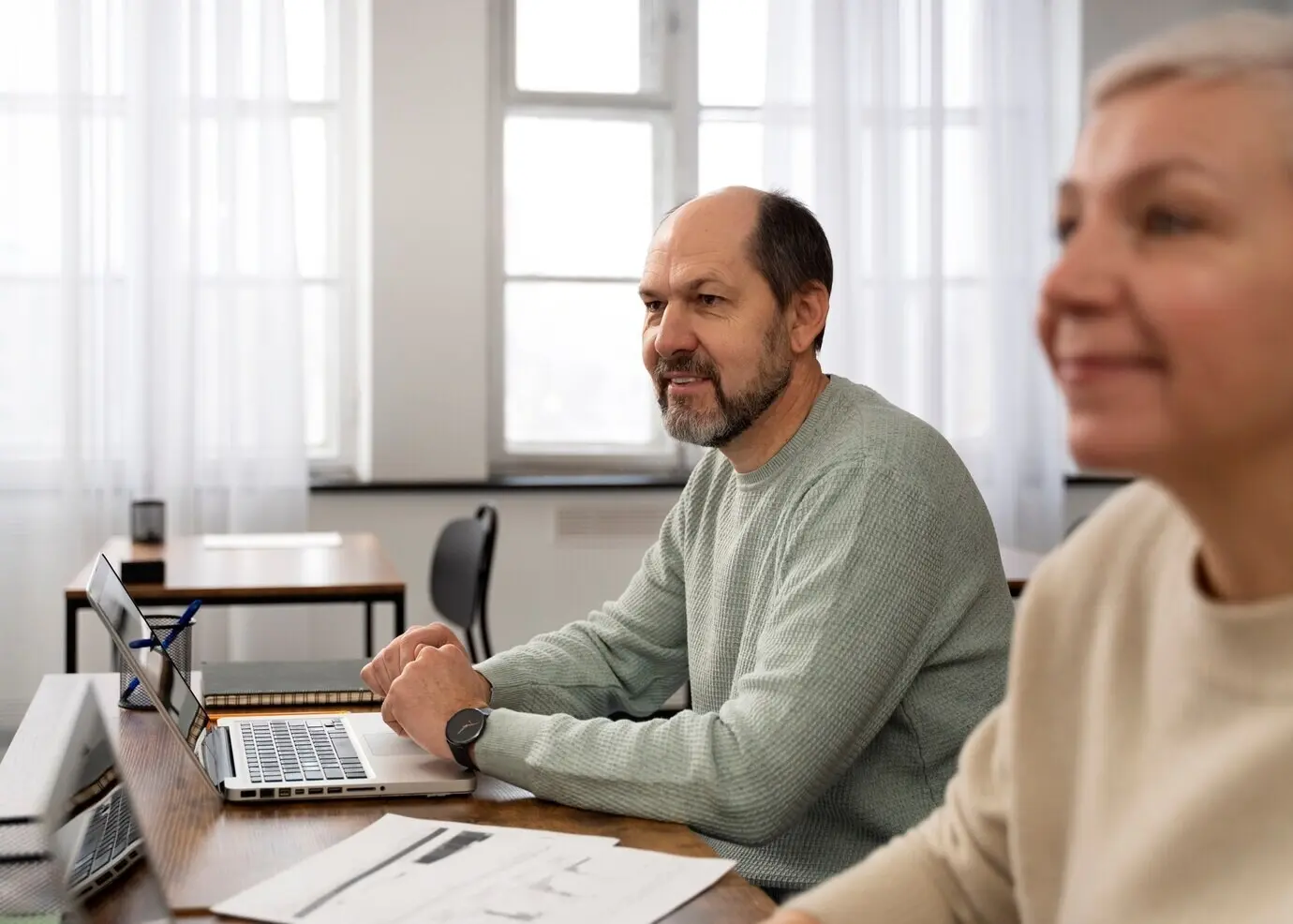 Пожилые люди в школе во время урока с ноутбуком.